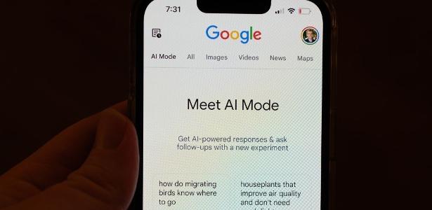 Modo IA do Google chega ao Brasil e ameaça tráfego Pessoa segura tela de celular em que aparece o Modo IA (AI Mode, em inglês)