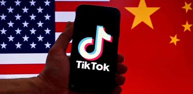 TikTok cria empresa conjunta nos EUA para evitar proibição no Celular com logo do TikTok e bandeiras dos EUA e da China ao fundo